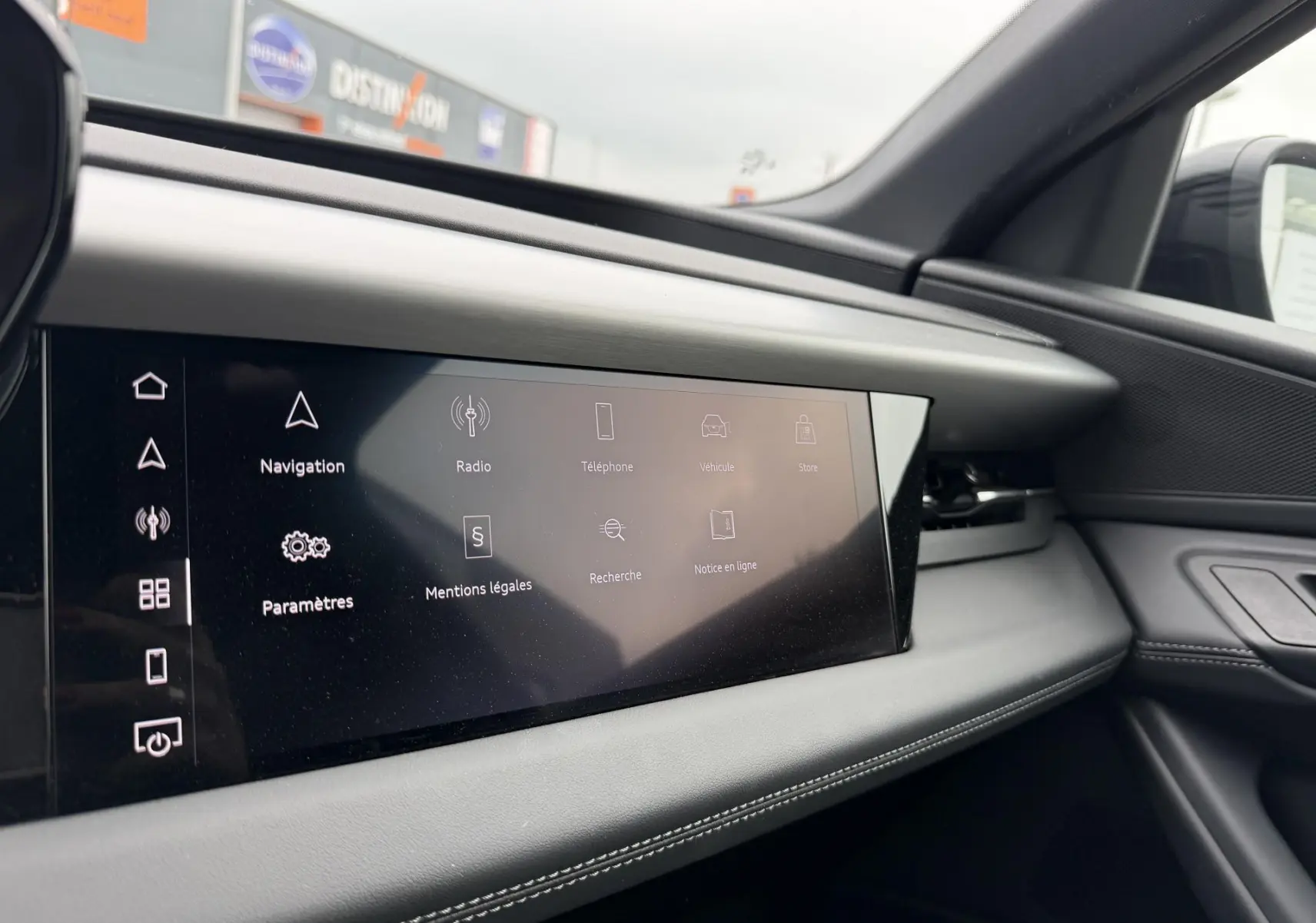 Vue intérieure du tableau de bord de l'Audi Q6 e-tron gris, avec écran tactile central affichant le menu paramètres.