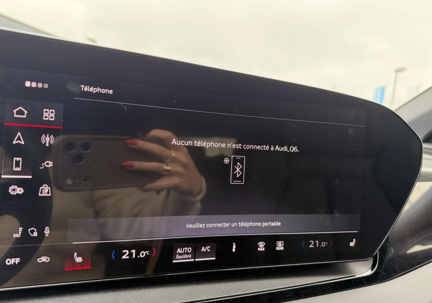 Écran tactile central de l'Audi Q6 e-tron 2024 affichant la connexion Bluetooth, avec tableau de bord noir et reflets visibles.