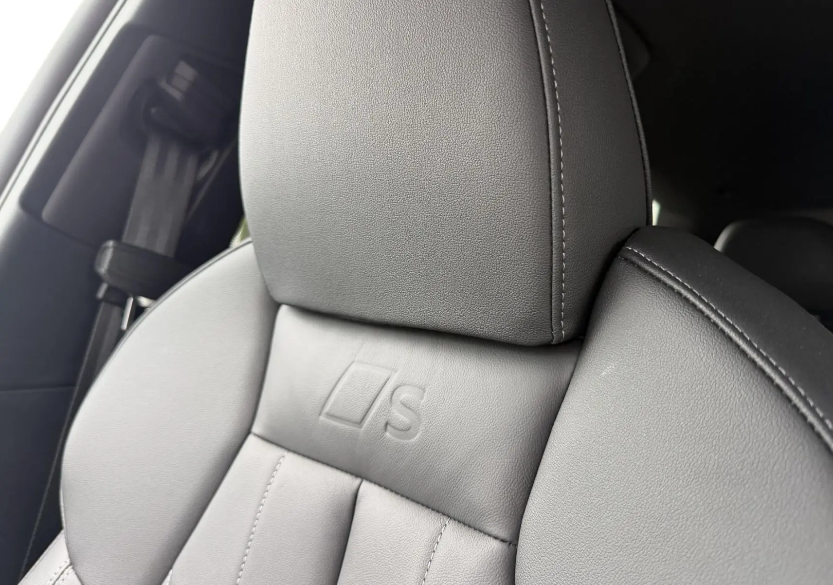 Gros plan sur l’appui-tête en cuir gris du siège avant avec logo S embossé, intérieur Audi Q6 e-tron 2024.