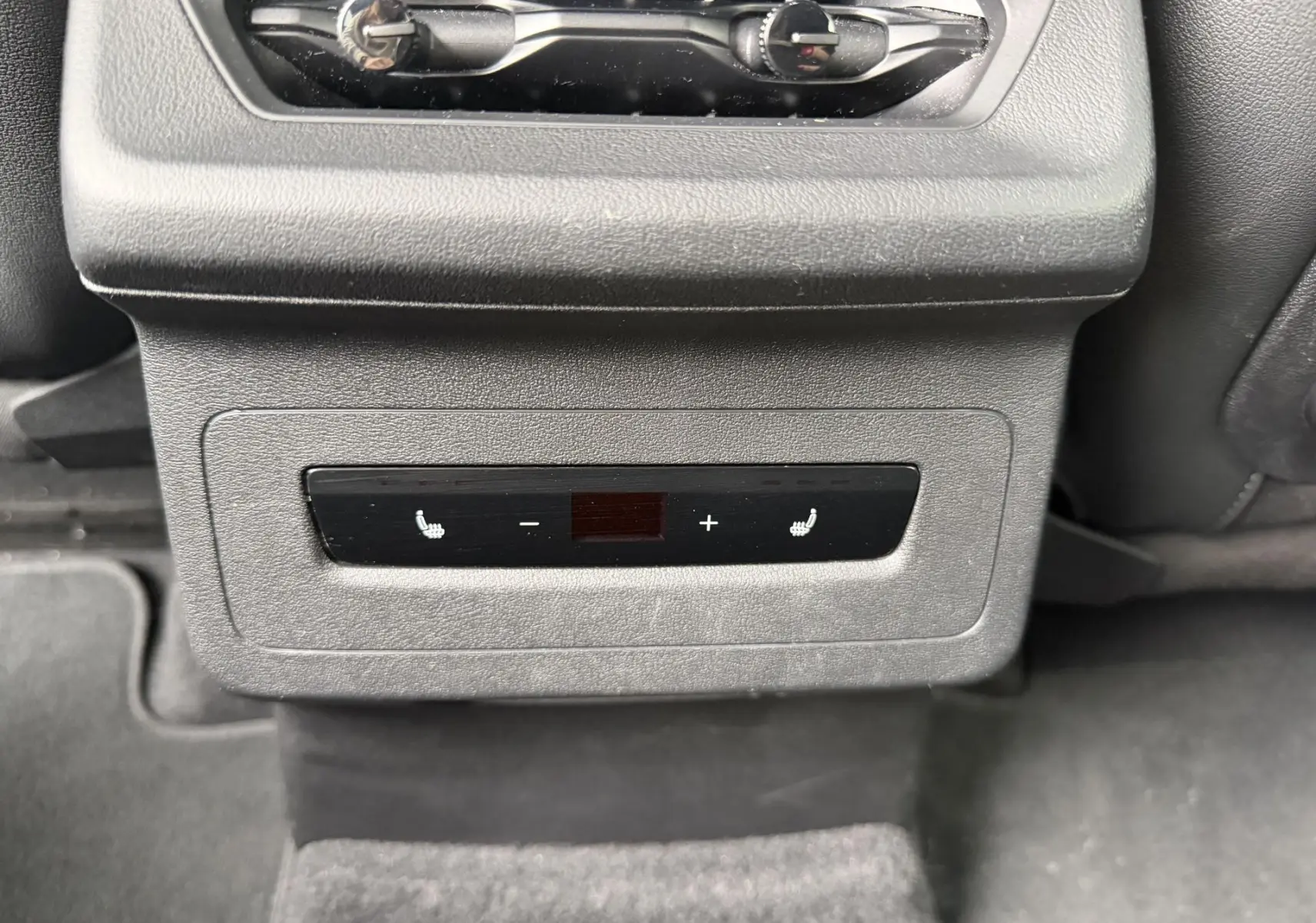 Vue rapprochée des commandes de chauffage des sièges arrière sur la console centrale d’un Audi Q6 e-tron gris.
