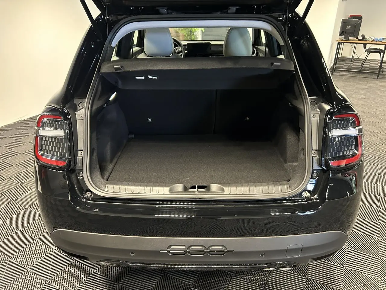Vue arrière du coffre ouvert de la FIAT 600 noire, mettant en valeur les feux arrière LED et l’espace de chargement vide.