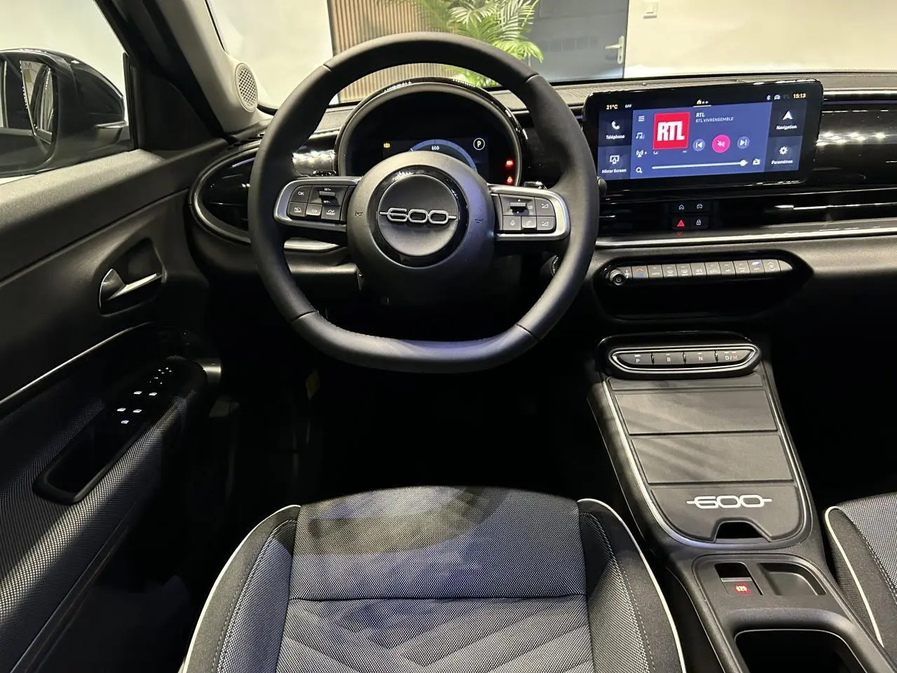 Vue intérieure centrée sur le volant et la console centrale noire du Fiat 600 avec écran tactile et sellerie bicolore.