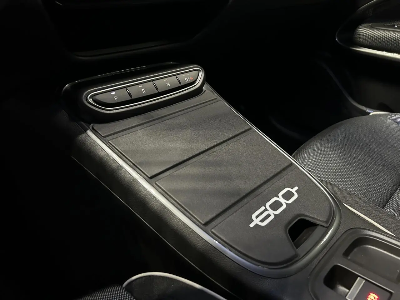 Gros plan sur la console centrale noire du Fiat 600 avec commandes de boîte auto et logo 600 blanc visible.
