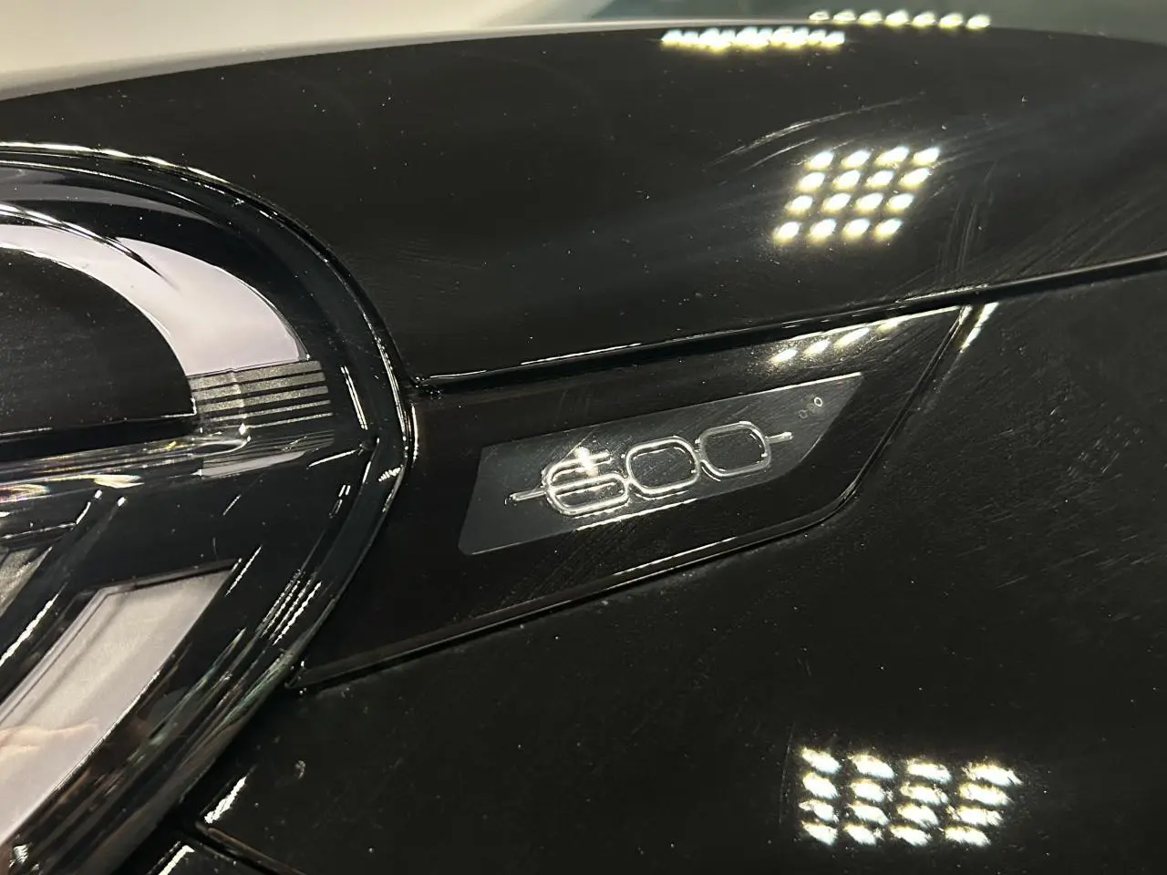 Gros plan sur le logo 600 argenté sur la calandre noire brillante d'une Fiat 600 hybride.