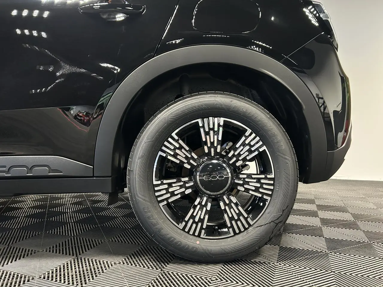Gros plan sur la roue arrière droite noire de la Fiat 600 hybride avec jante alliage noire et détails argentés.