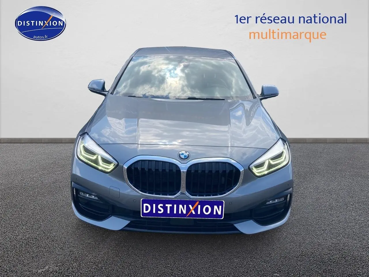 Vue frontale d'une BMW Série 1 gris foncé avec phares LED allumés et calandre double haricot caractéristique.