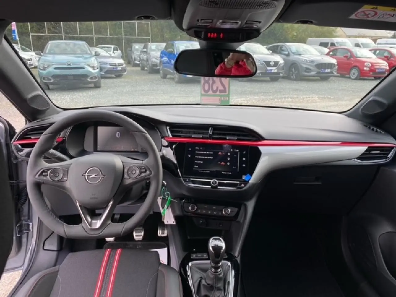 Intérieur de l’Opel Corsa gris magnetic, vue du poste de conduite avec volant, écran tactile et détails rouges sur la planche de bord.