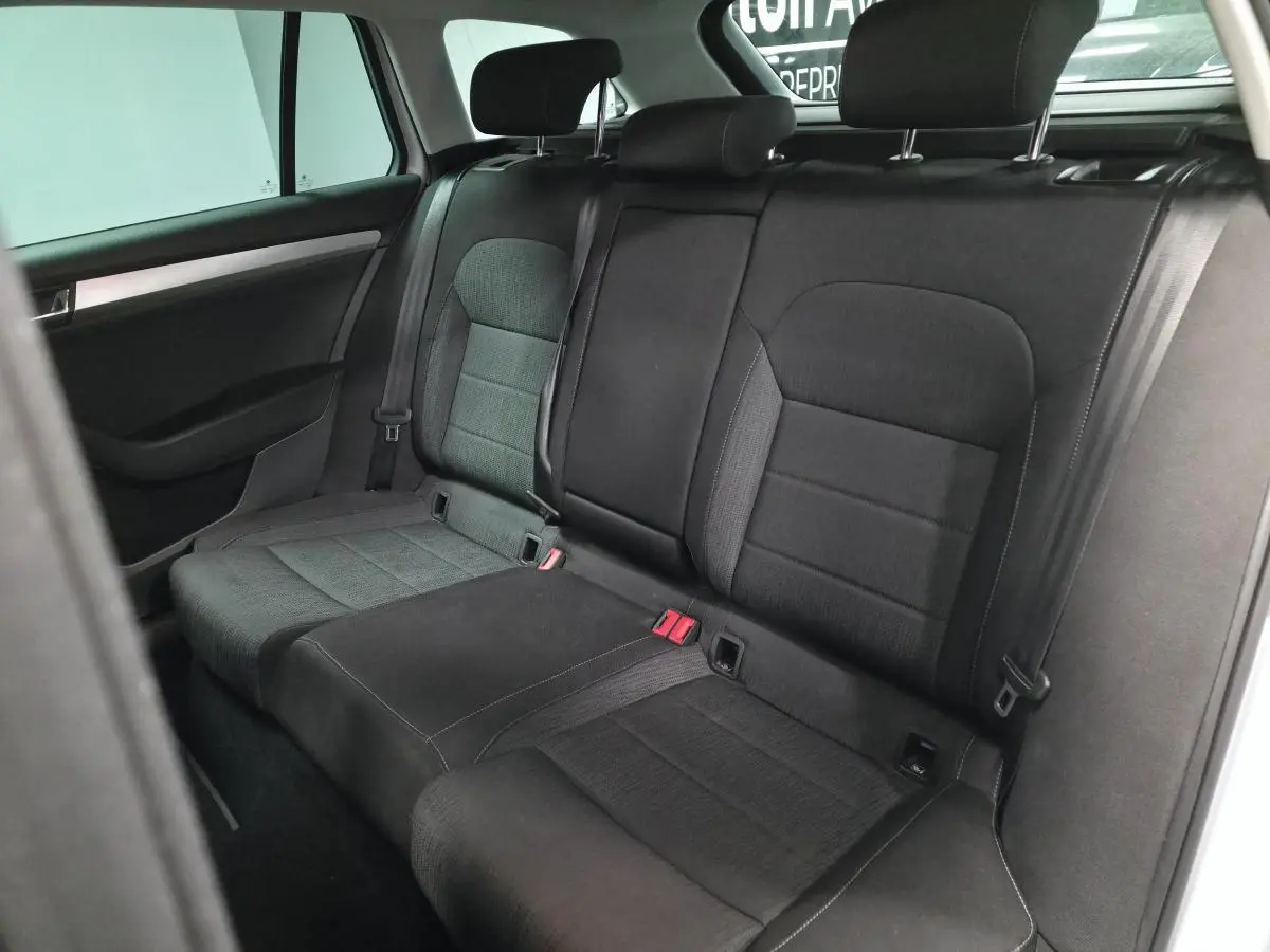 Vue intérieure montrant la banquette arrière noire avec appuie-têtes réglables d'une Skoda Superb Combi blanche.
