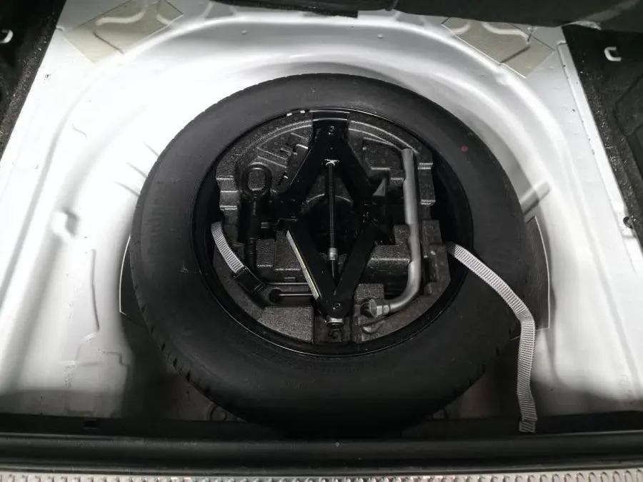 Vue plongeante sur la roue de secours et le cric dans le coffre blanc d'une Skoda Superb Combi 2018.