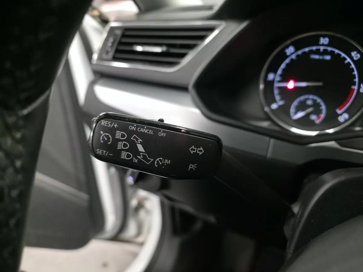 Gros plan sur la manette de commande noire du régulateur de vitesse dans l'habitacle d'une Skoda Superb Combi blanche.