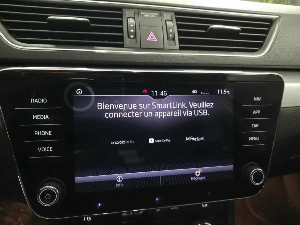 Écran tactile central du tableau de bord de la Skoda Superb Combi blanc, affichant SmartLink et commandes autour.