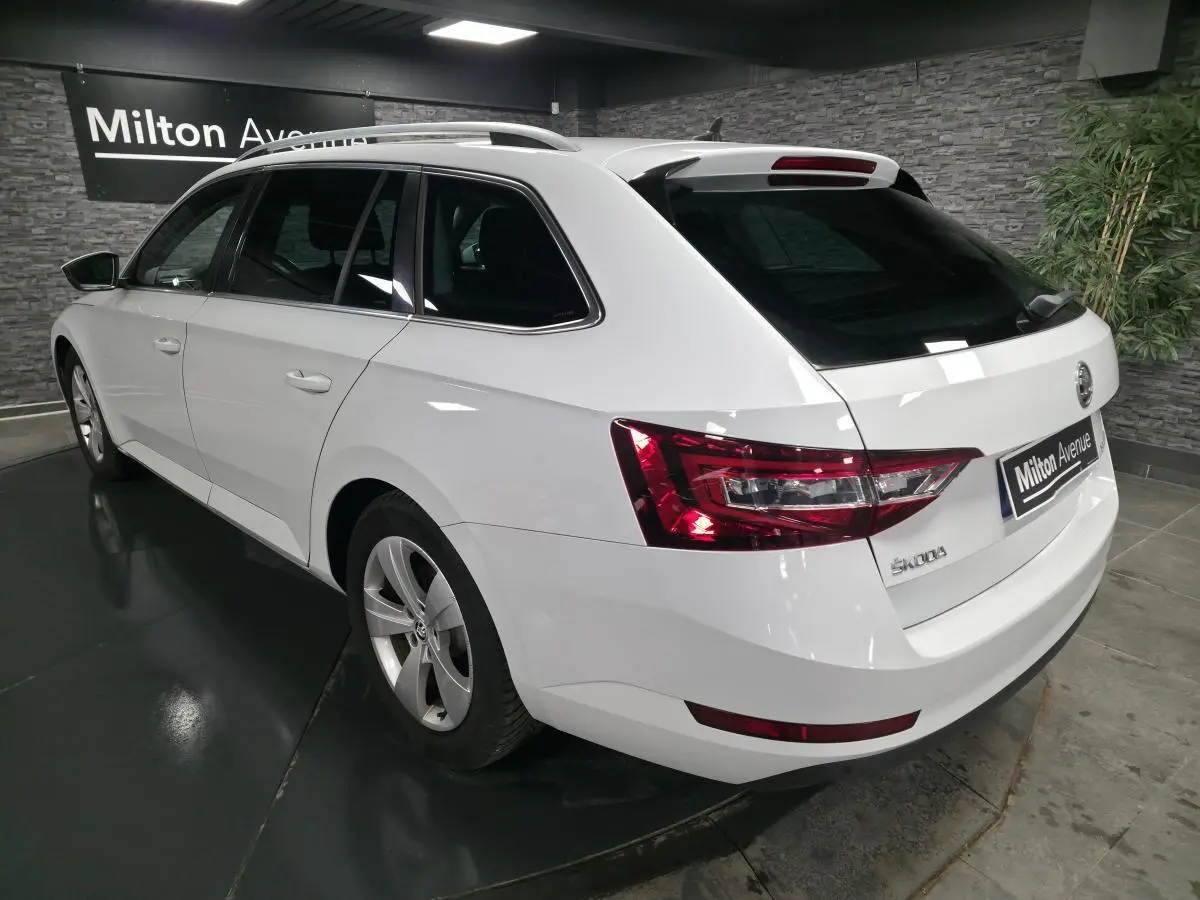 Vue 3/4 arrière droite d'un break SKODA SUPERB blanc avec feux arrière LED et jantes alliage 17 pouces.