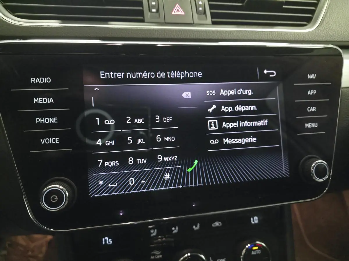 Écran tactile central du tableau de bord de la Skoda Superb Combi blanc, affichant le clavier pour entrer un numéro de téléphone.