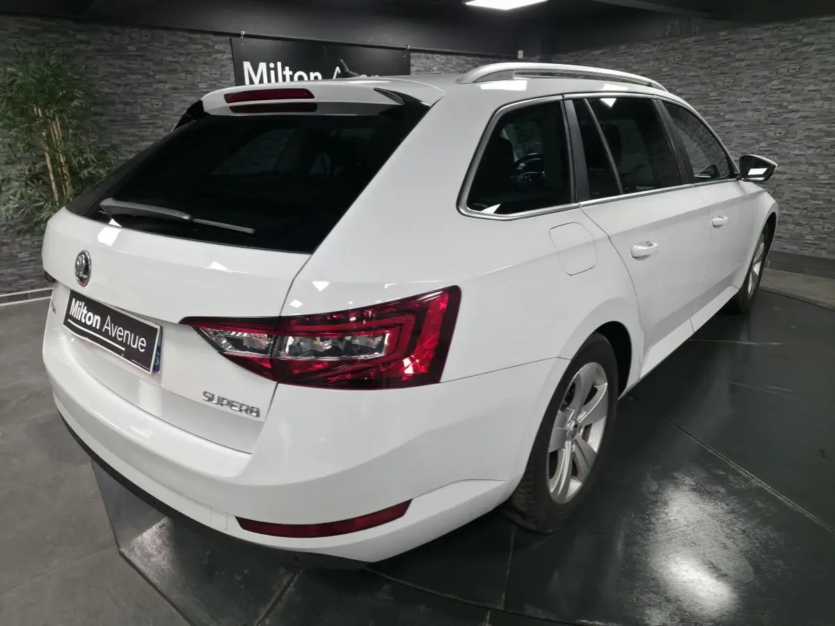 Vue 3/4 arrière droite d'un break SKODA SUPERB blanc avec feux arrière LED et jantes alliage 17 pouces.