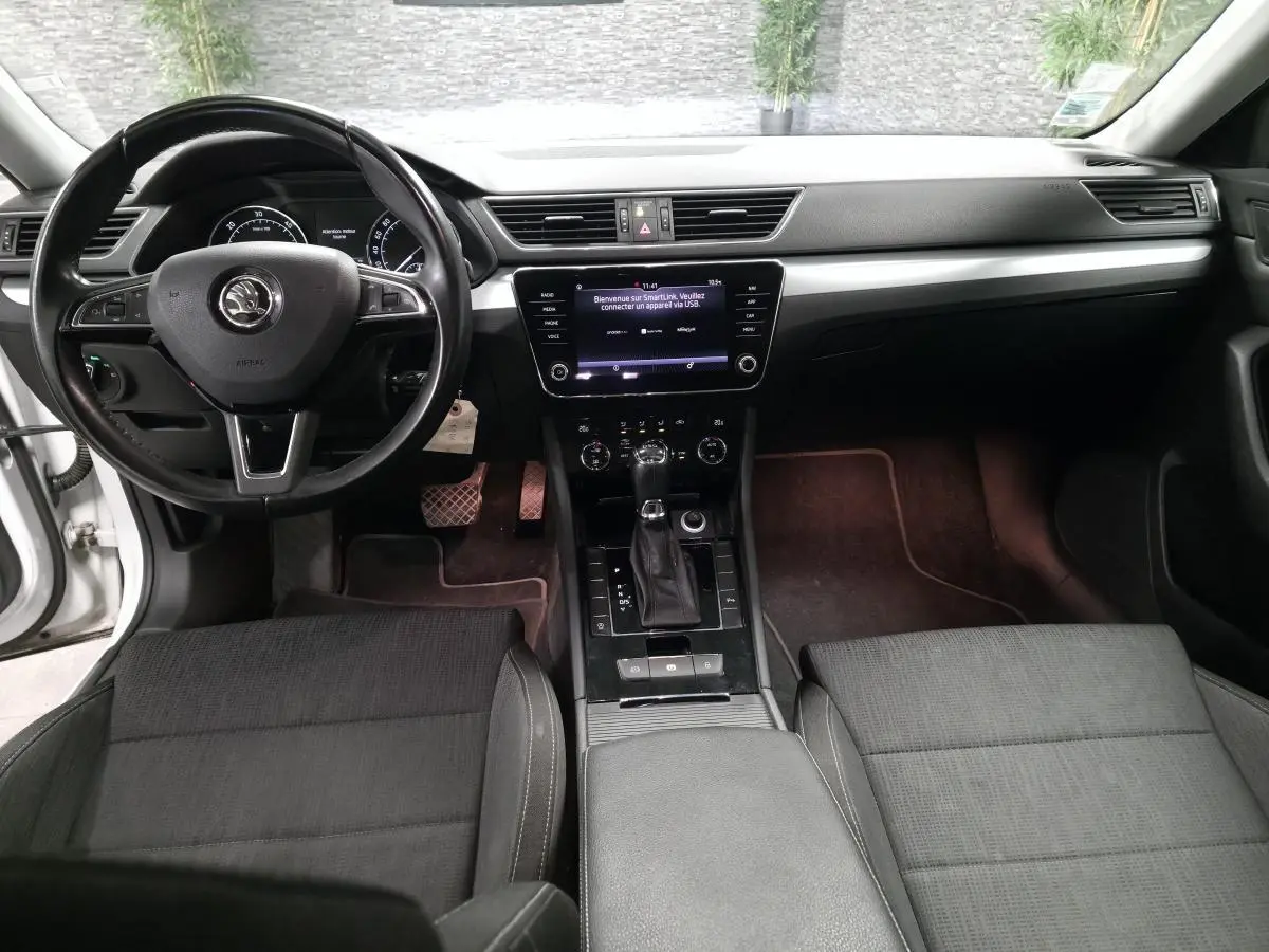 Intérieur noir de la Skoda Superb Combi 2018 vu de face, avec tableau de bord moderne et écran tactile central.