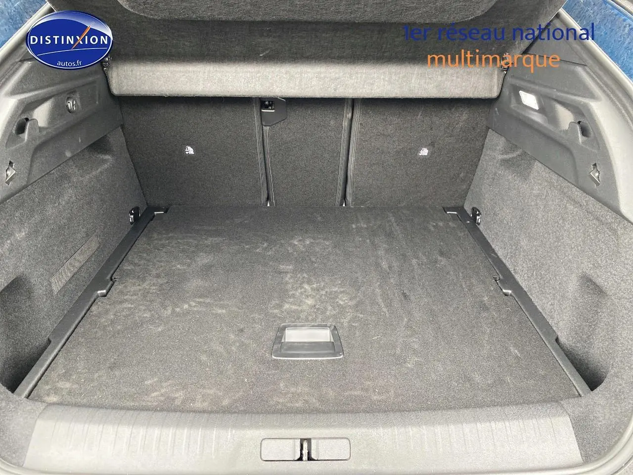 Coffre ouvert en vue arrière d’un Peugeot 3008 bleu, montrant un espace de chargement spacieux et tapis noir.