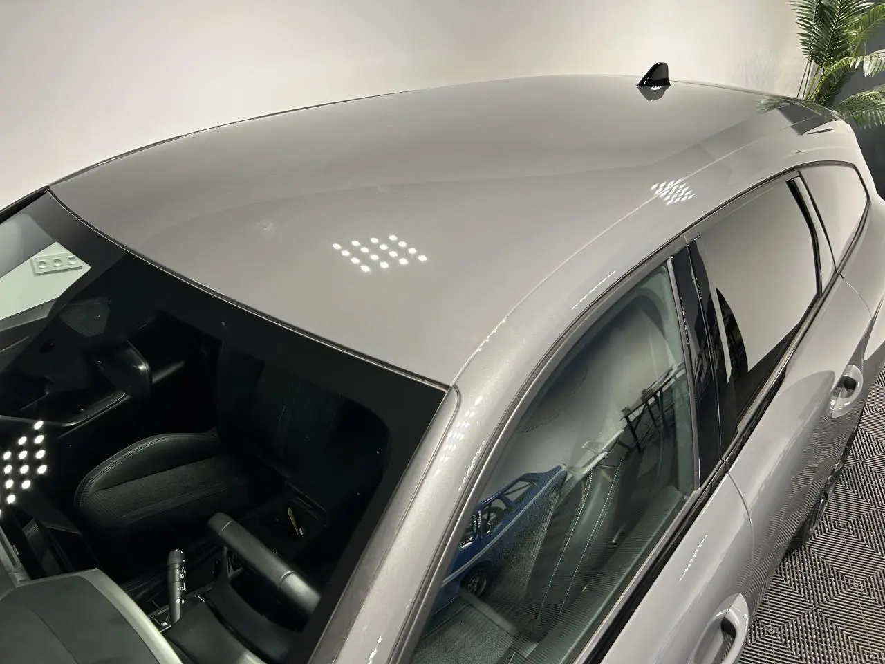Vue plongeante côté gauche sur le break Peugeot 308 SW gris Sélénium avec vitres teintées et toit lisse.
