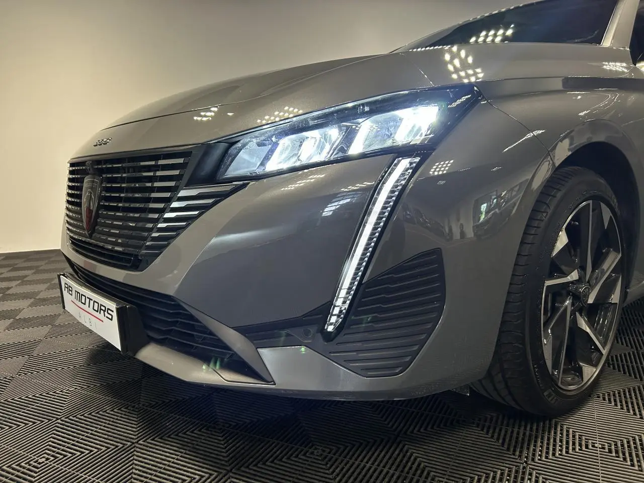 Vue 3/4 avant droit d'une Peugeot 308 SW hybride gris Sélénium avec phares LED et jantes alliage 17 pouces.