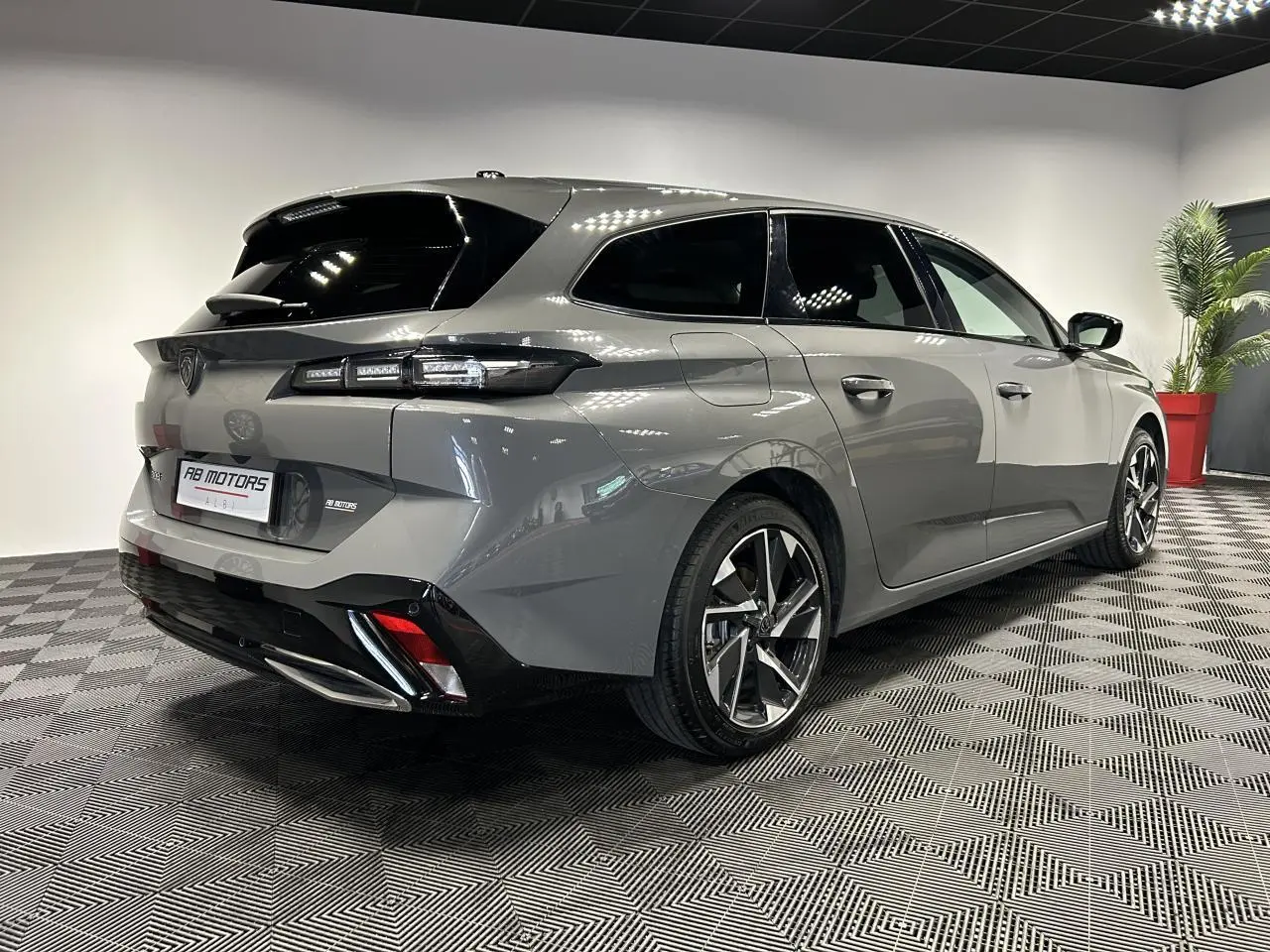 Vue 3/4 arrière droit d'une Peugeot 308 SW gris Sélénium avec jantes alliage 17'' et feux LED distinctifs.
