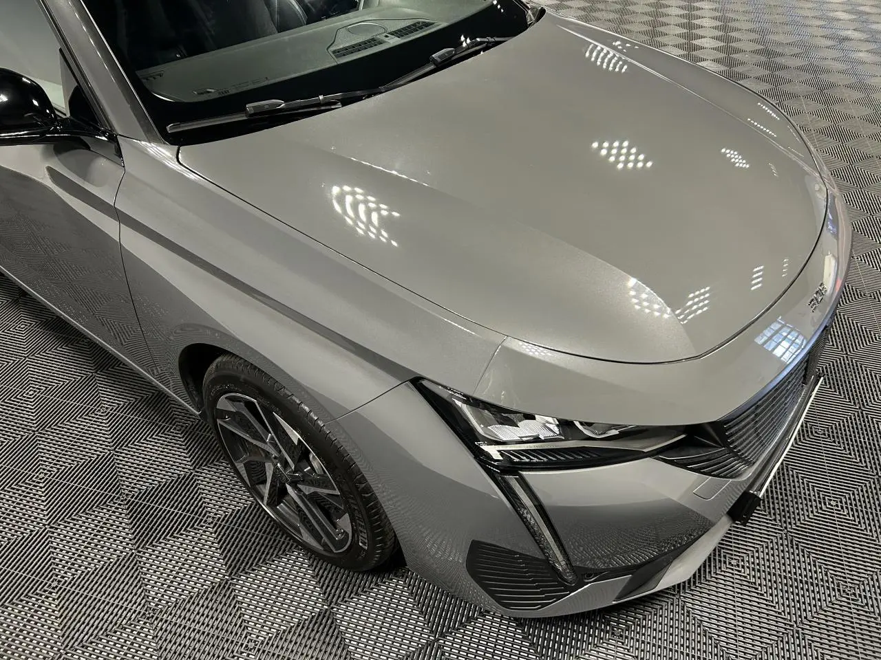 Vue 3/4 avant gauche d'une Peugeot 308 SW gris Sélénium avec jantes alliage noires et calandre noire brillante.