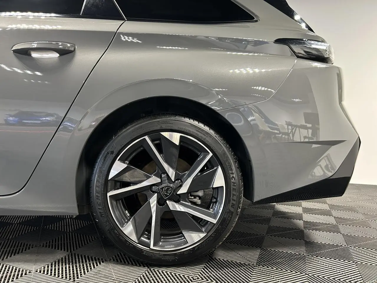 Gros plan sur la roue arrière droite et la carrosserie gris Sélénium d'une Peugeot 308 SW 2025 avec jante alliage 17'' Halong.