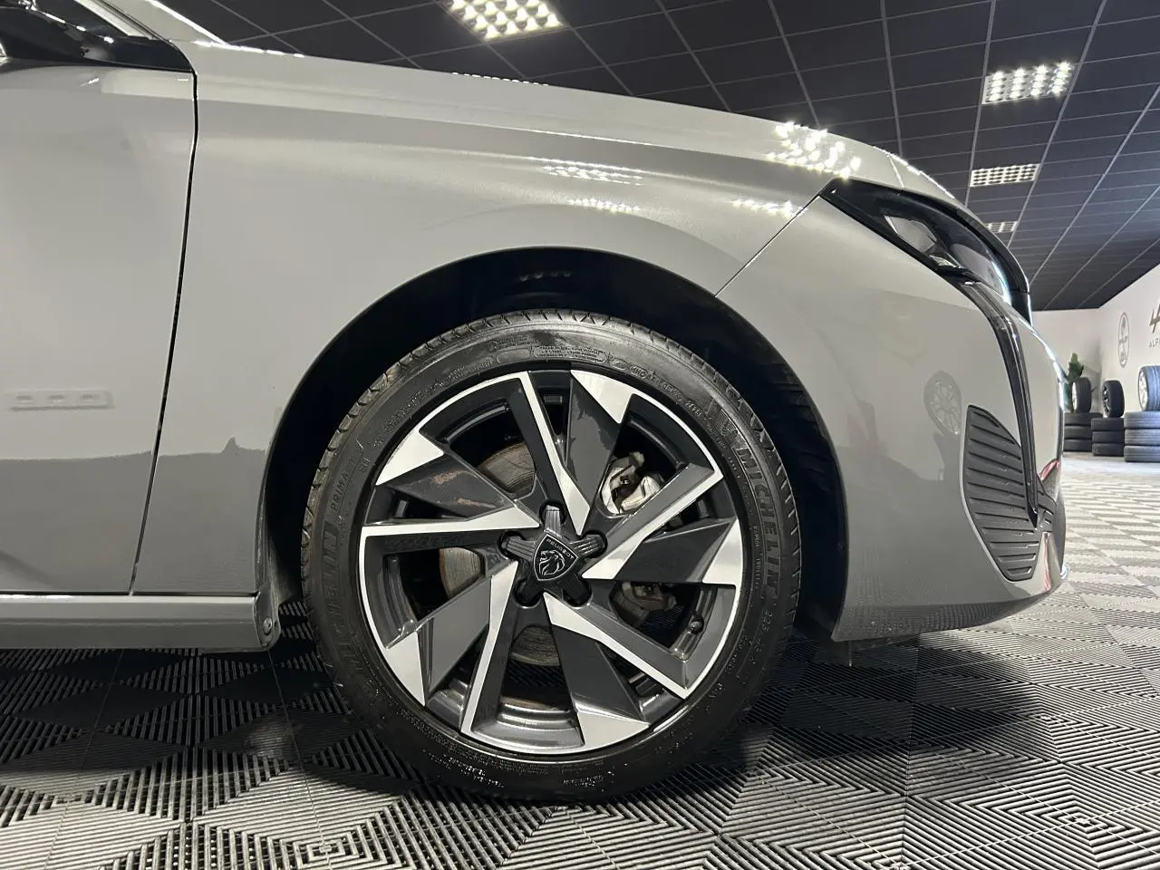 Gros plan sur la roue avant droite de la Peugeot 308 SW gris Sélénium avec jante alliage 17'' Halong diamantée.