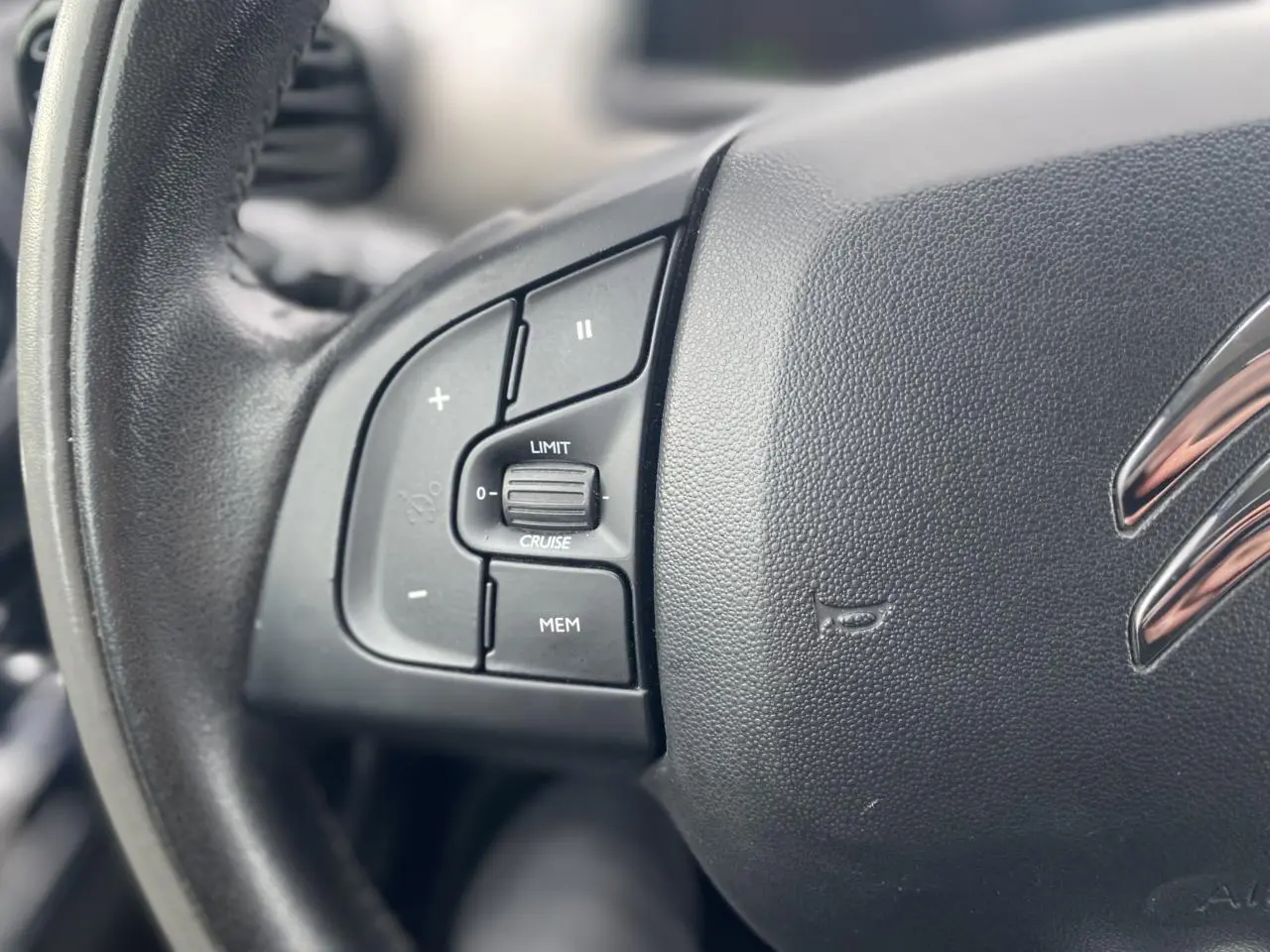 Gros plan sur le volant noir de la Citroën C4 Cactus 2015, montrant les commandes du régulateur de vitesse côté gauche.
