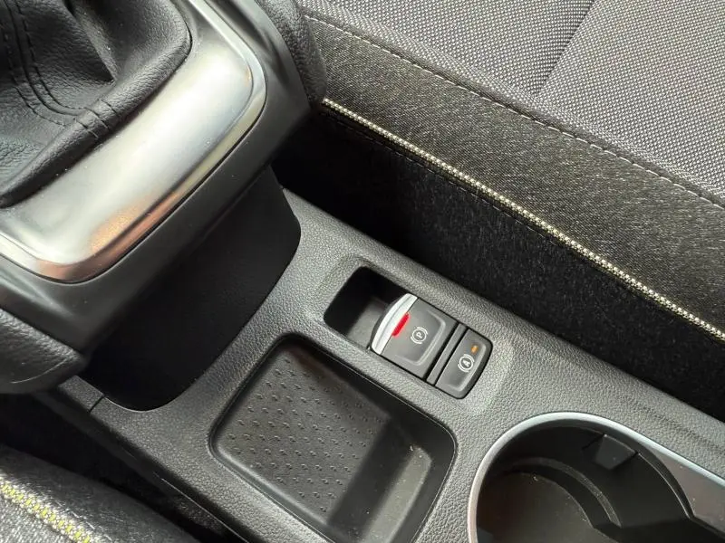 Gros plan intérieur sur la console centrale du Renault Captur 2025 bleu Iron/Noir Étoilé, avec frein à main électrique et bouton Auto Hold.