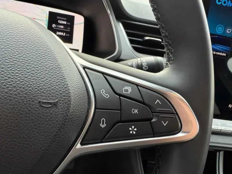 Gros plan sur les commandes au volant côté droit du Renault Captur 2025, cuir noir et finition argentée.