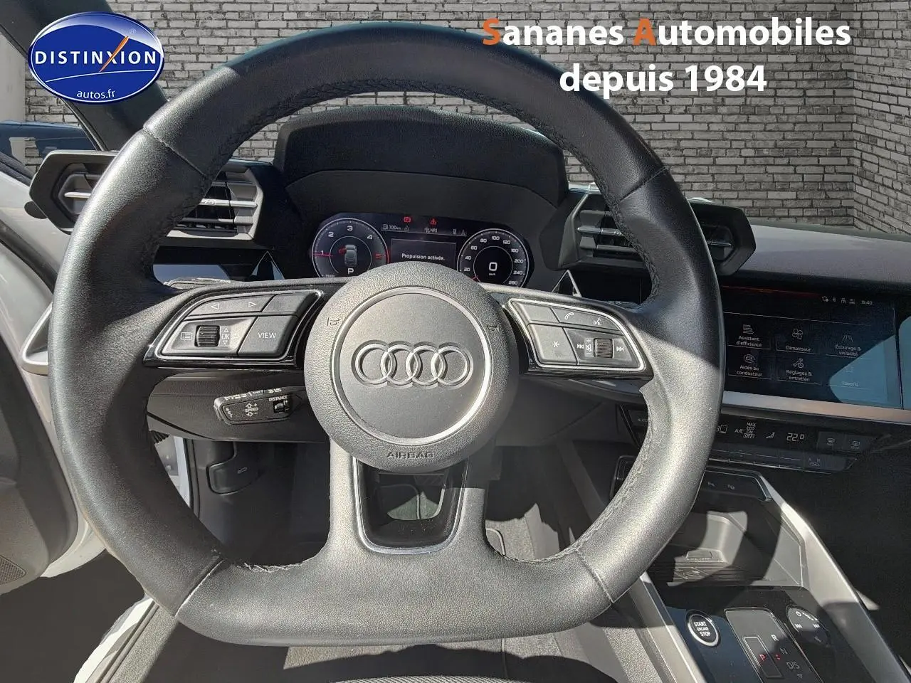 Vue intérieure centrée sur le volant cuir sport multifonctions de l'Audi A3 Sportback blanc 2023.