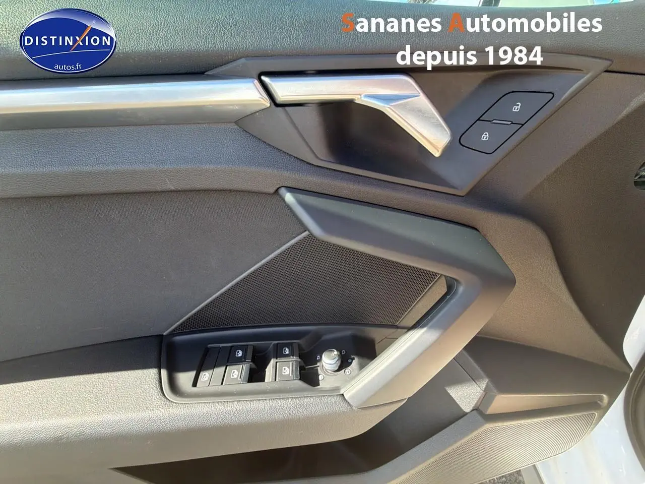 Détail de la porte avant gauche de l'Audi A3 Sportback blanche 2023, montrant les commandes de vitres et la poignée intérieure.