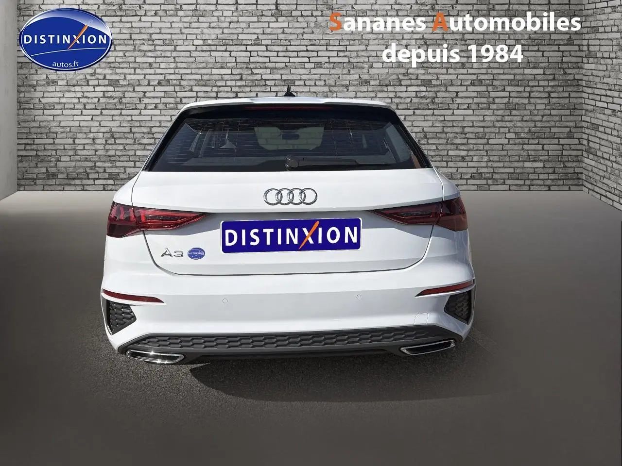 Vue arrière d'une Audi A3 Sportback blanche 2023, avec feux LED et double sortie d'échappement intégrée.