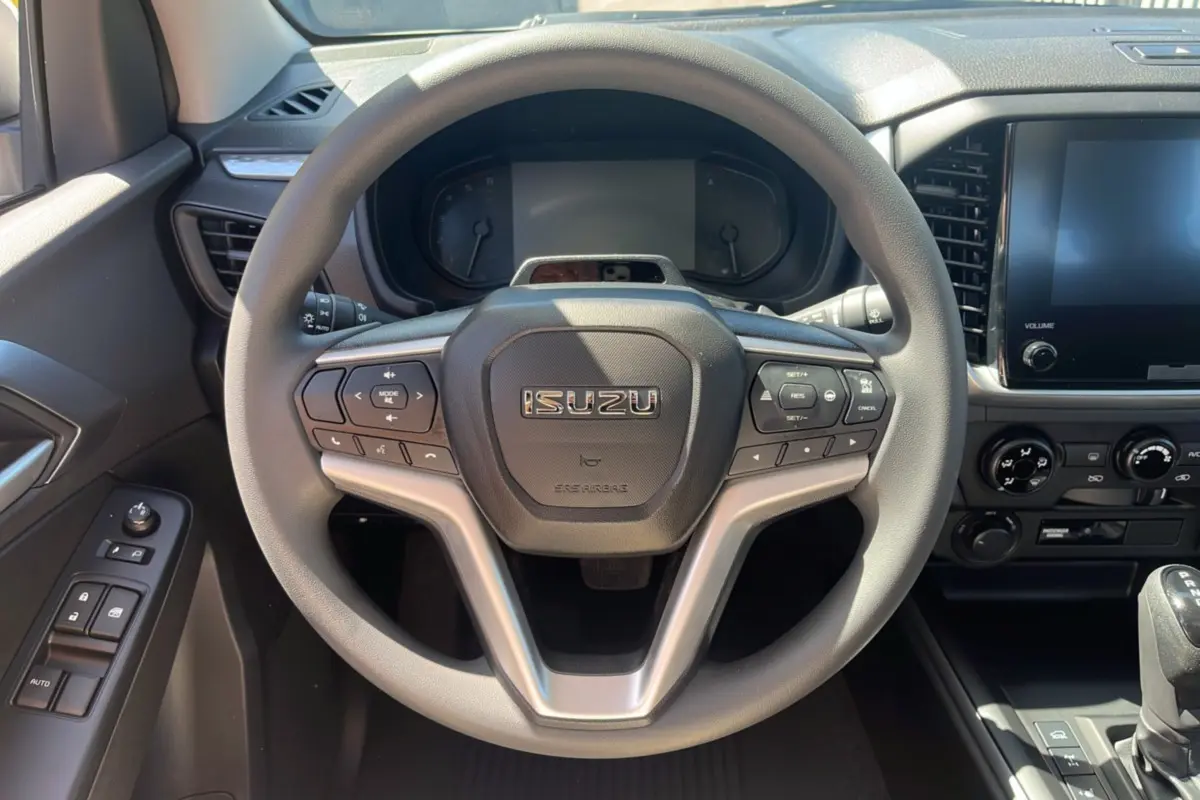 Vue rapprochée du volant multifonctions gris de l'Isuzu D-MAX 2026 avec tableau de bord et écran tactile.