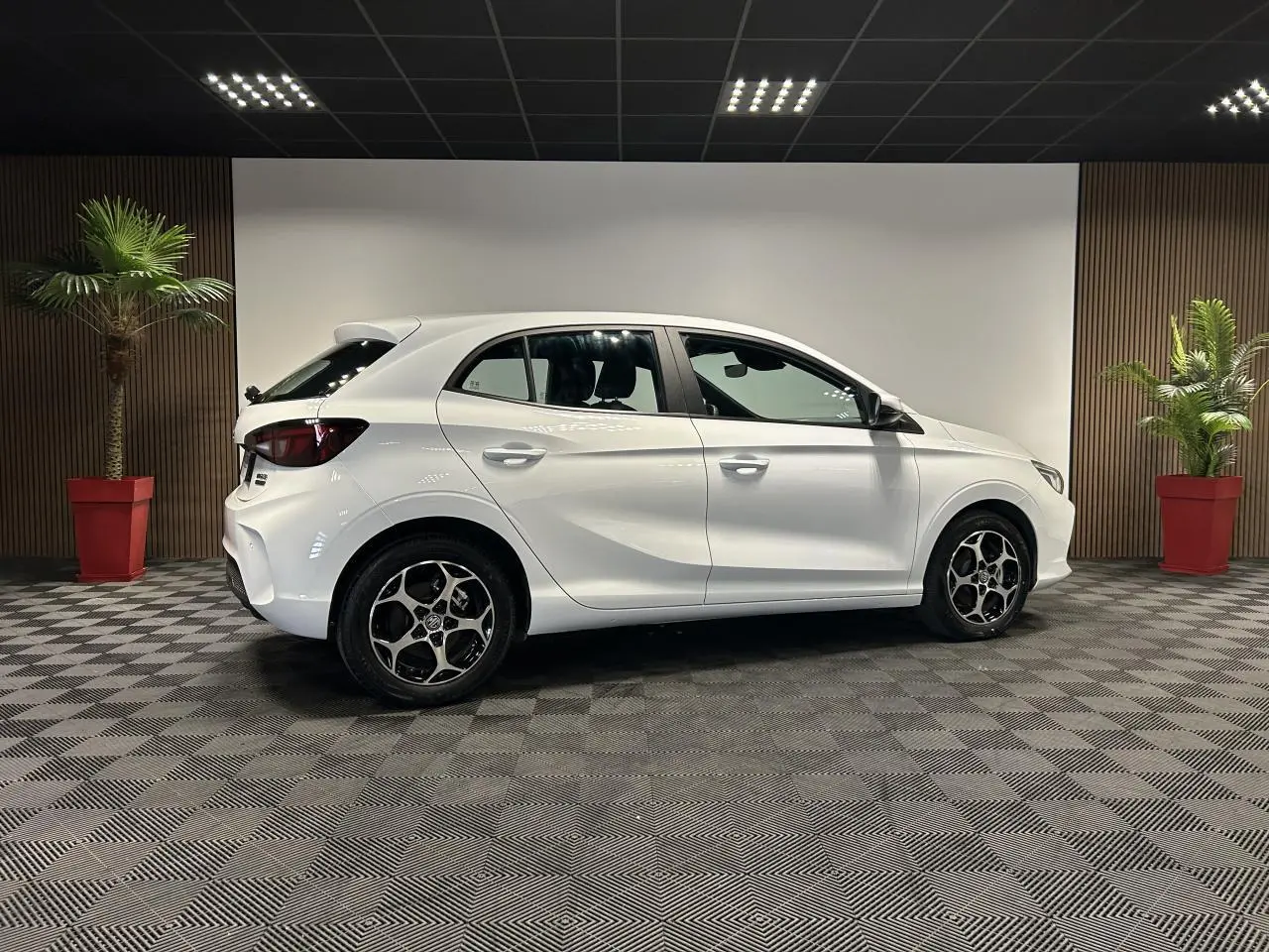 Vue de profil côté gauche d'une MG3 blanche 2025 en hybride, avec jantes alliage et intérieur noir visible.