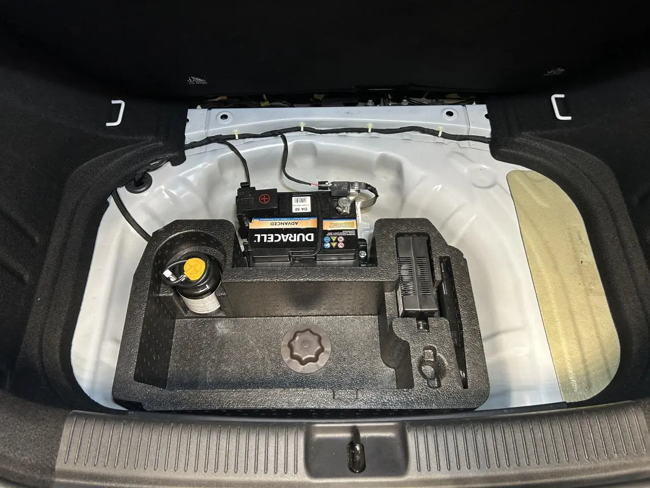 Vue plongeante sur le coffre ouvert d'une MG3 blanche, montrant la batterie et le rangement sous plancher.