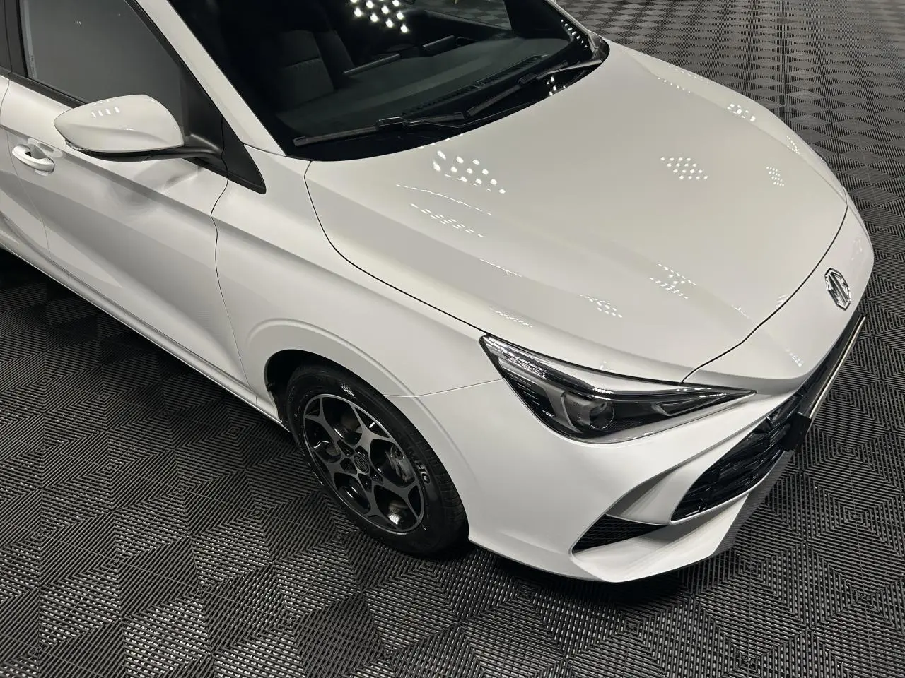 Vue 3/4 avant droit de la MG3 1.5 Hybrid+ blanche avec jantes alliage noires et phares halogènes.