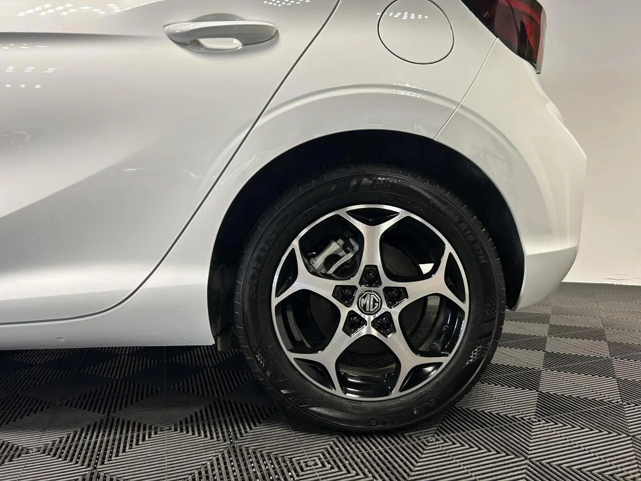 Gros plan sur la roue arrière droite en alliage noir et argent d’une MG3 blanche 2025.