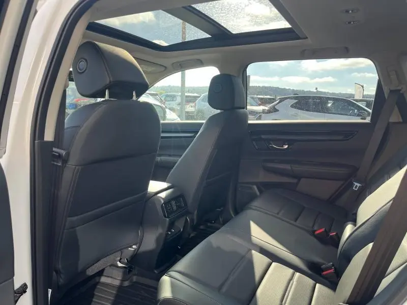 Vue intérieure arrière du Honda CR-V 2024 avec sièges en cuir noir et toit panoramique en verre lumineux