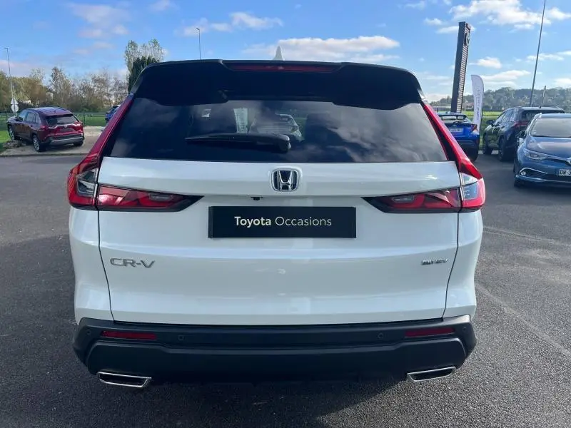 Vue arrière d'un Honda CR-V blanc avec feux LED et double sortie d'échappement chromée sur parking extérieur.