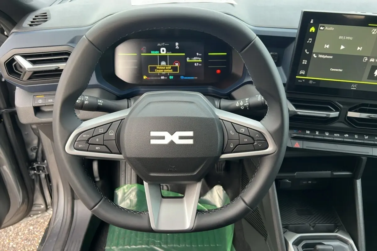Vue rapprochée du volant multifonctions et du tableau de bord numérique du Dacia Duster HEV 140 noir nacré, version 2025.
