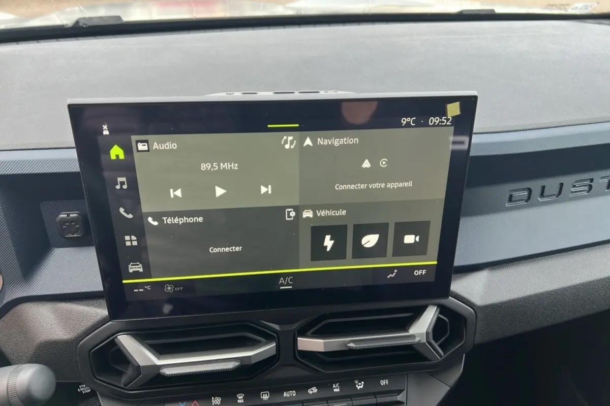 Vue intérieure du tableau de bord du Dacia Duster 2025 avec écran tactile et inscription DUSTER en relief sur la planche.