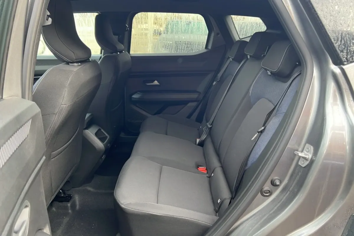 Vue intérieure sur les sièges arrière du Dacia Duster 2025 noir nacré, montrant un habillage tissu gris foncé et bleu.