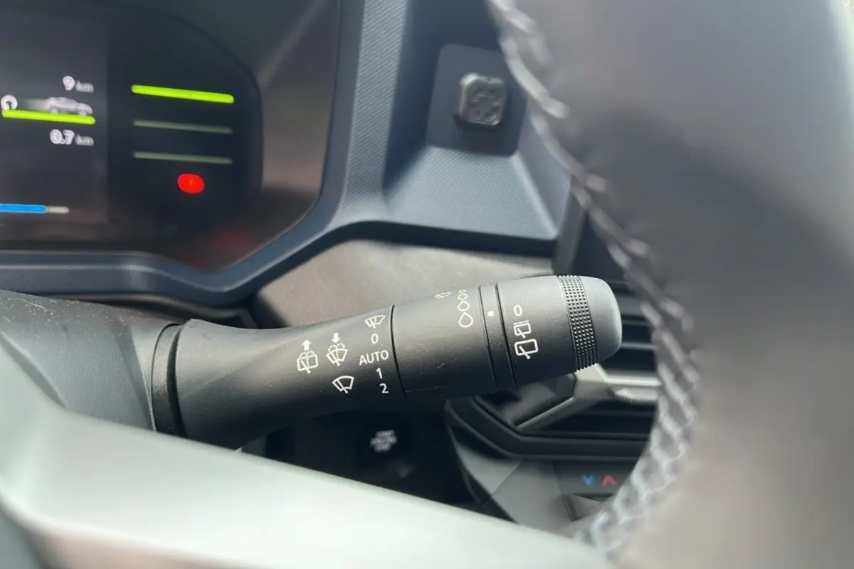 Gros plan sur la commande d'essuie-glace du tableau de bord d'un Dacia Duster 2025 noir nacré HEV 140 Journey Pack City.