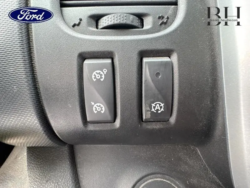 Gros plan sur les commandes de régulateur de vitesse et arrêt/redémarrage auto du moteur du Renault Trafic blanc glacier.