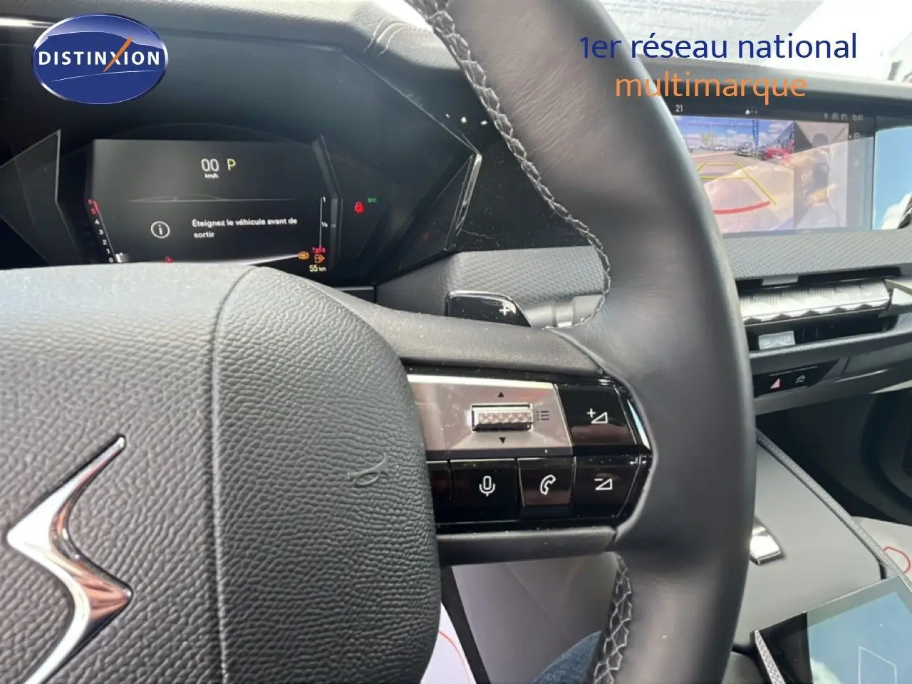 Vue rapprochée du volant cuir noir et du tableau de bord numérique du DS4 2024, avec écran multimédia et caméra de recul affichée.