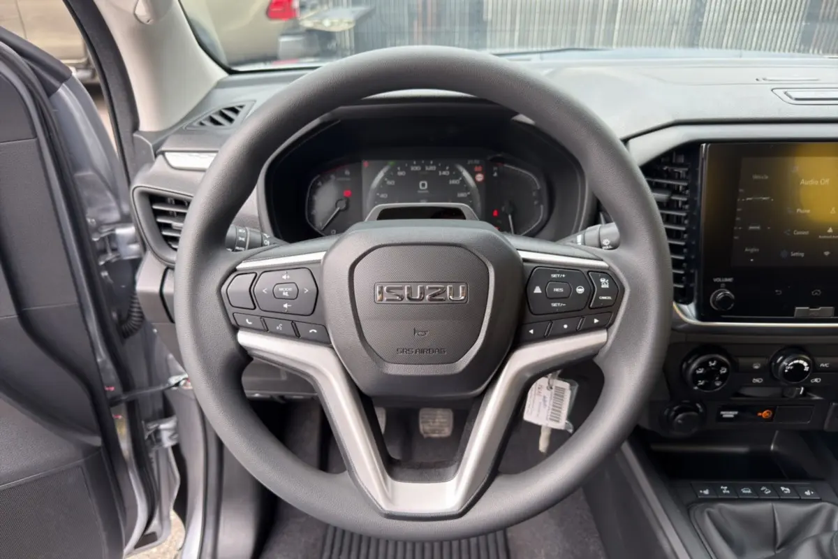 Vue intérieure centrée sur le volant multifonctions d’un Isuzu D-MAX gris Mercury avec tableau de bord et écran tactile.