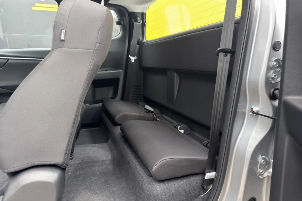 Vue intérieure côté droit du pick-up Isuzu D-MAX 2026 Mercury silver, montrant les sièges arrière rabattus en tissu noir.