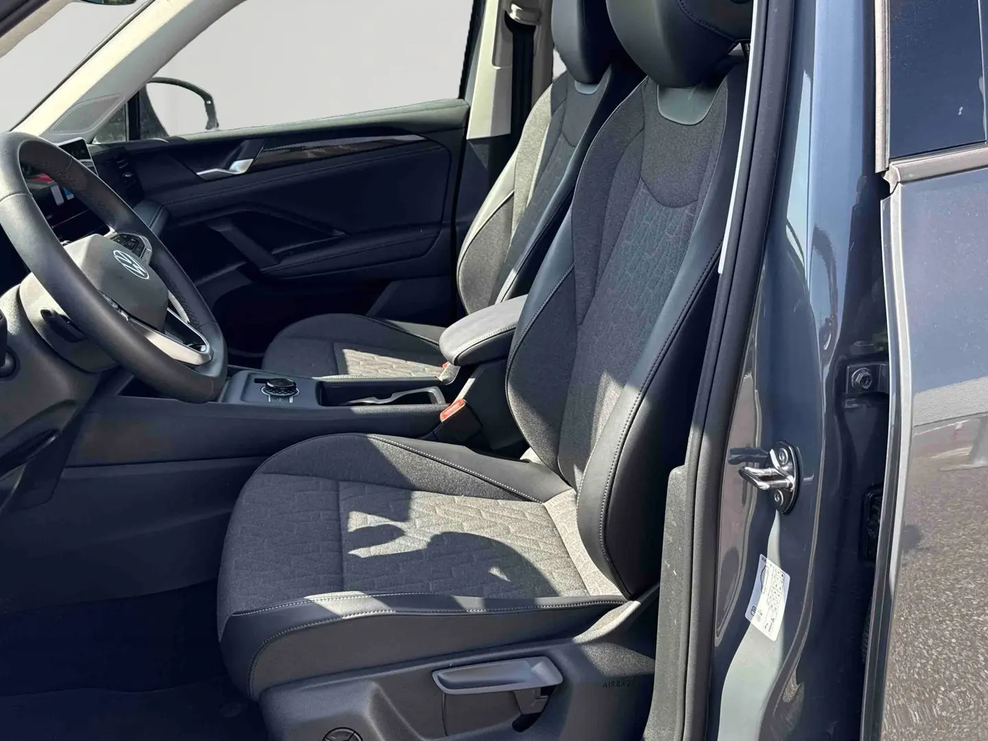Vue intérieure côté conducteur du Volkswagen Tiguan 2025 gris, avec sièges tissu et cuir et volant multifonction.