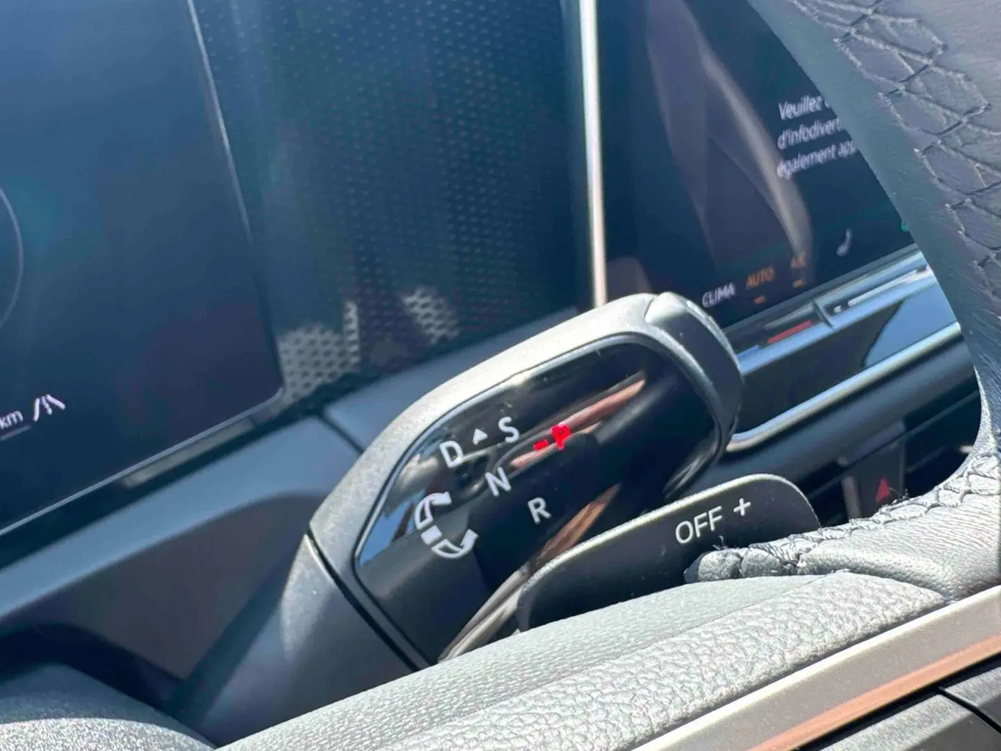 Gros plan sur le levier de vitesses noir brillant du Volkswagen Tiguan eHybrid 2025, avec tableau de bord en arrière-plan.