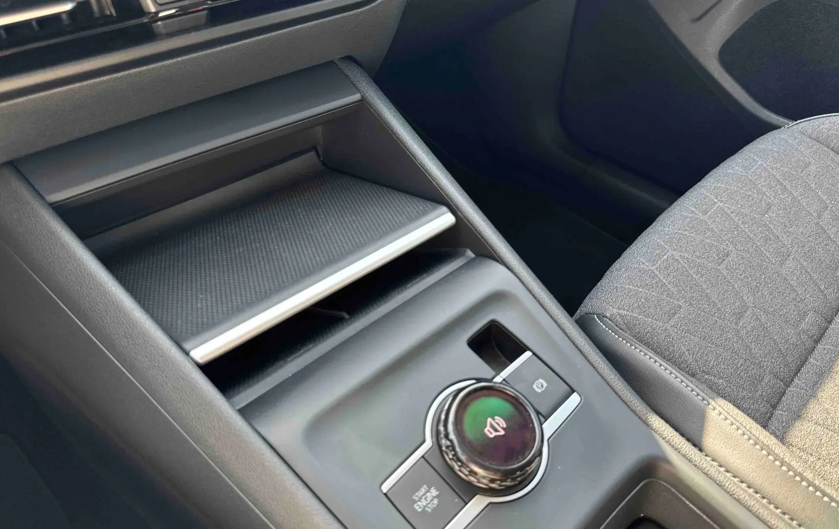 Vue rapprochée de la console centrale grise du Volkswagen Tiguan 2025 avec molette de contrôle et frein à main électrique.
